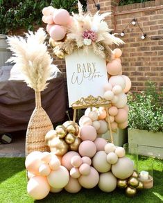 a baby shower sign surrounded by balloons and other decorations on the grass in front of a brick building