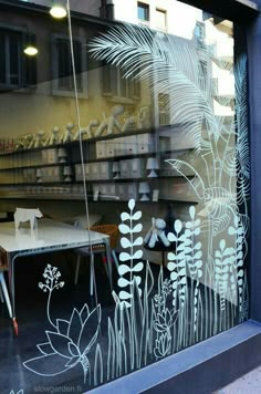 the window is decorated with white flowers and plants on it's glass, as well as birds