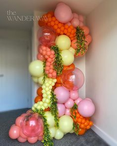 the balloon wall is decorated with oranges, pinks and white balloons in various colors