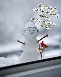 a snowman with a hat and two skis standing in the snow next to a window