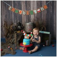 a baby sitting on the floor with a cake in front of him and some decorations