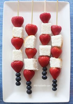 strawberries and blueberries are arranged on skewers with marshmallows