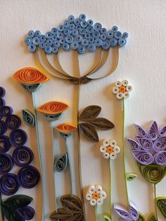 paper quilled flowers are arranged on a white surface