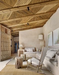 a living room filled with lots of furniture and wooden ceiling beams in an open area