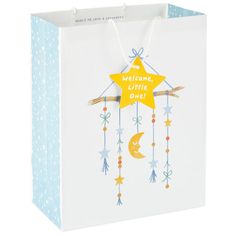 a white shopping bag with a yellow star hanging from it's side and the words welcome, little one on top