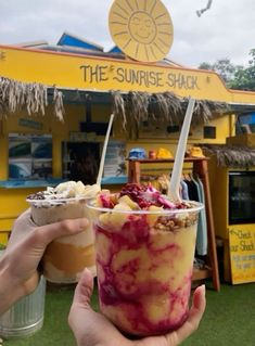 a person holding up an ice cream sundae in front of a yellow and blue building