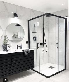 a black and white bathroom with two mirrors on the wall, a sink, and a walk in shower