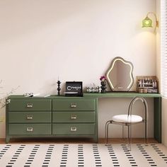 a green dresser sitting next to a white chair in a room with black and white flooring