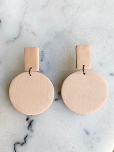 two round wooden earrings sitting on top of a marble counter