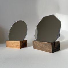 two mirrors sitting next to each other on top of a wooden stand