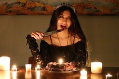 a woman in a tiara is holding a knife over a cake with lit candles