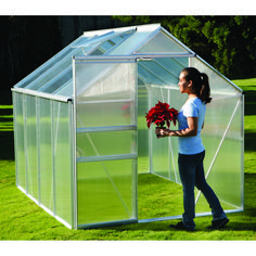 a woman standing in front of a green house holding a bouquet of flowers and looking at it