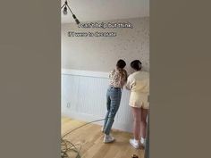 two women are painting the walls in their house