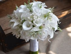 a bouquet of white flowers sitting on top of a wooden bench