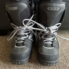 a pair of black and grey snow boots with laces on the bottom, sitting on a carpeted floor