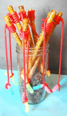 some candy sticks are in a jar with red and yellow straws sticking out of them