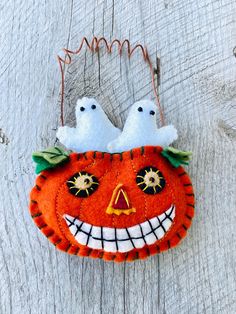 two white birds sitting on top of an orange pumpkin ornament with green leaves