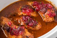 two pieces of chicken covered in sauce and garnished with cranberries