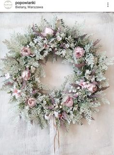 a wreath is hanging on the wall next to a white cloth with pink flowers and greenery