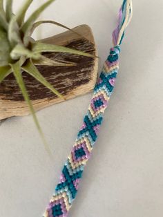 a close up of a bracelet on a table next to a small airplant