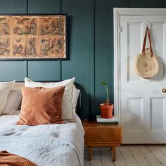 a bed sitting next to a white door in a room with green walls and wooden floors