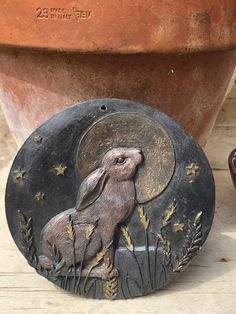 a ceramic rabbit sitting on top of a wooden table next to a potted plant