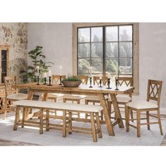 a dining room table and chairs in front of a window with a stone wall behind it