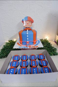 a box filled with cupcakes sitting on top of a table next to a cake