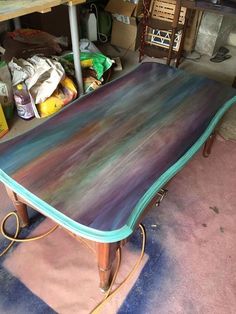 an old table is being painted with blue and purple paint on it's sides