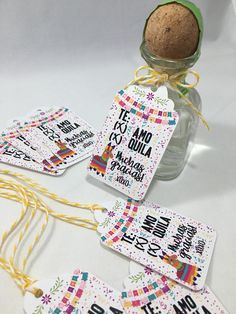 some tags are hanging from a bottle with a cork in it on a white table