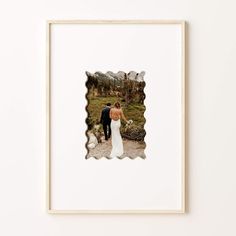 a framed photograph of a bride and groom walking in the mountains with their arms around each other