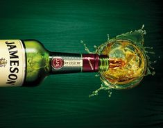 a bottle of jameson being poured into a glass with water splashing on the side