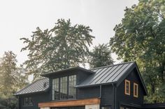 a black house in the woods with lots of trees