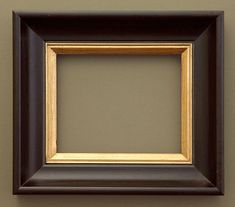 an empty black and gold frame hanging on the wall above a toilet paper dispenser