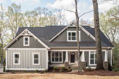 a gray house with white trim in the woods