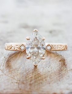 an oval shaped diamond ring on top of a piece of wood