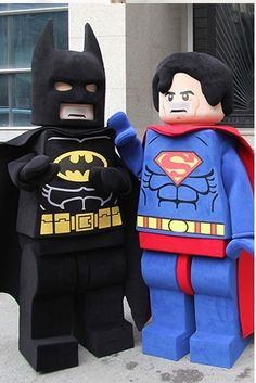 two lego batmans standing next to each other in front of a building with windows