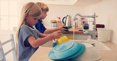 two children are washing dishes in the kitchen