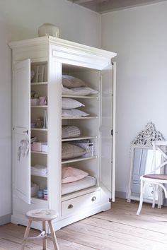 a white armoire in a room with wooden floors