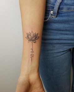 a woman's arm with a tattoo on the wrist that has a flower and words