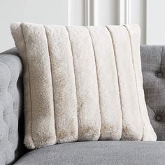 a white pillow sitting on top of a gray couch