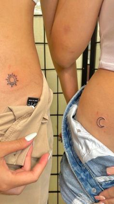 two women with small tattoos on their stomachs, one is holding a cell phone