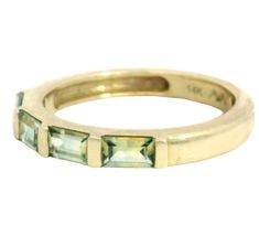 a yellow gold band with green stones