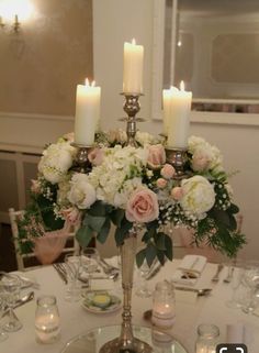 a centerpiece with flowers and candles on a table