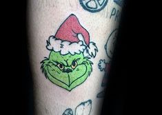 the grin face has been tattooed on someone's leg and is wearing a santa hat