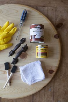 some tools are sitting on top of a wooden table next to a pair of yellow gloves