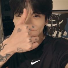 a young man with tattoos on his arm and hand in front of him, making the peace sign