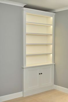 an empty white bookcase in the corner of a room with gray walls and beige carpet