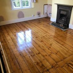 an empty room with wood floors and a fire place