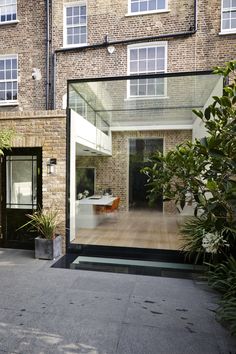 an outside view of a brick building with glass doors and plants in the foreground